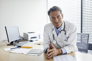 Portrait of smiling male doctor sitting at desk